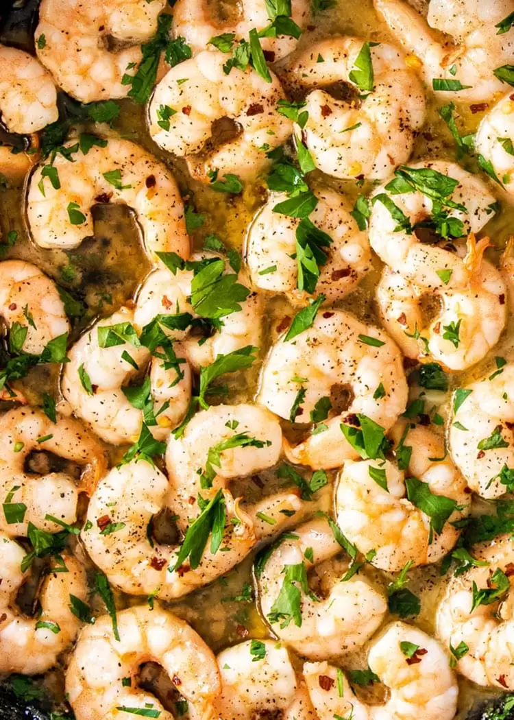 closeup of garlic butter shrimp garnished with fresh parlsey.