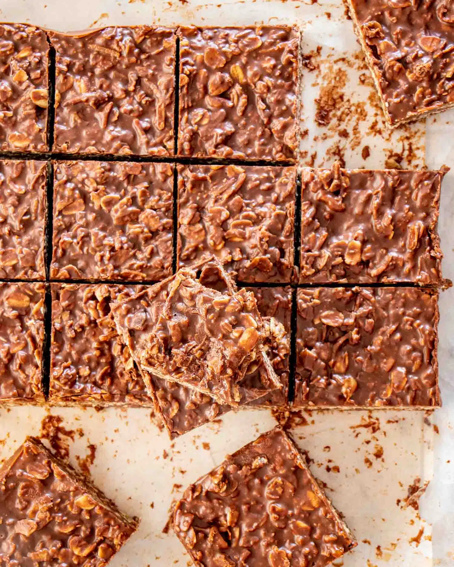 no bake peanut butter chocolate bars cut into pieces on a piece of parchment paper.