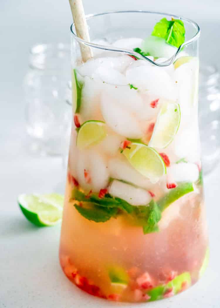 a pitcher filled with mojito and chopped up strawberries