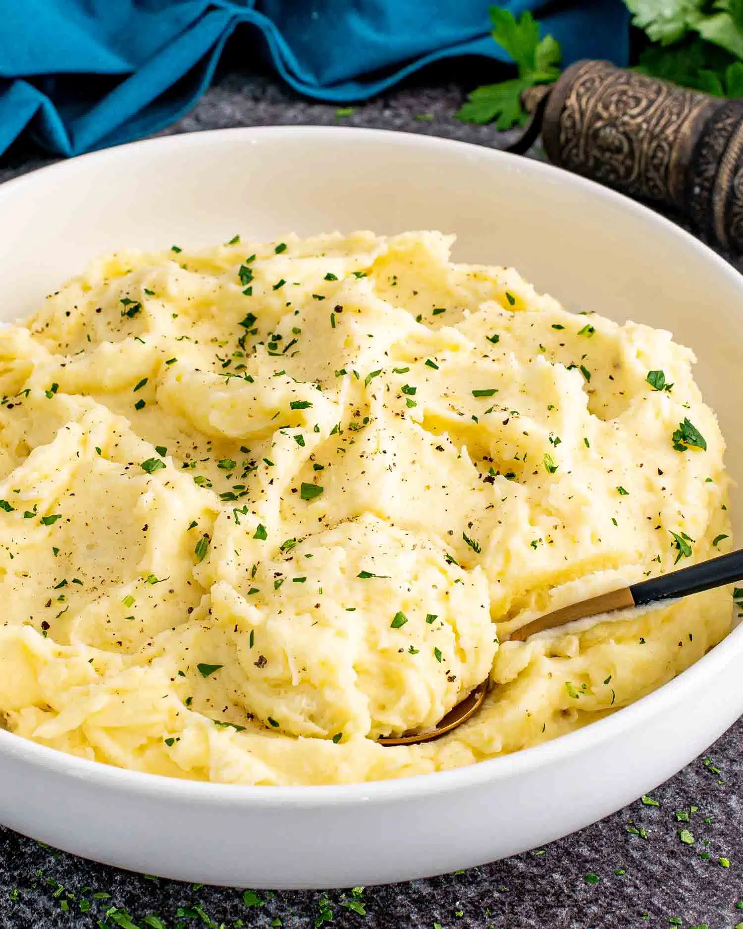a big white bowl with freshly made mashed potatoes and garnished with a bit of parsley.