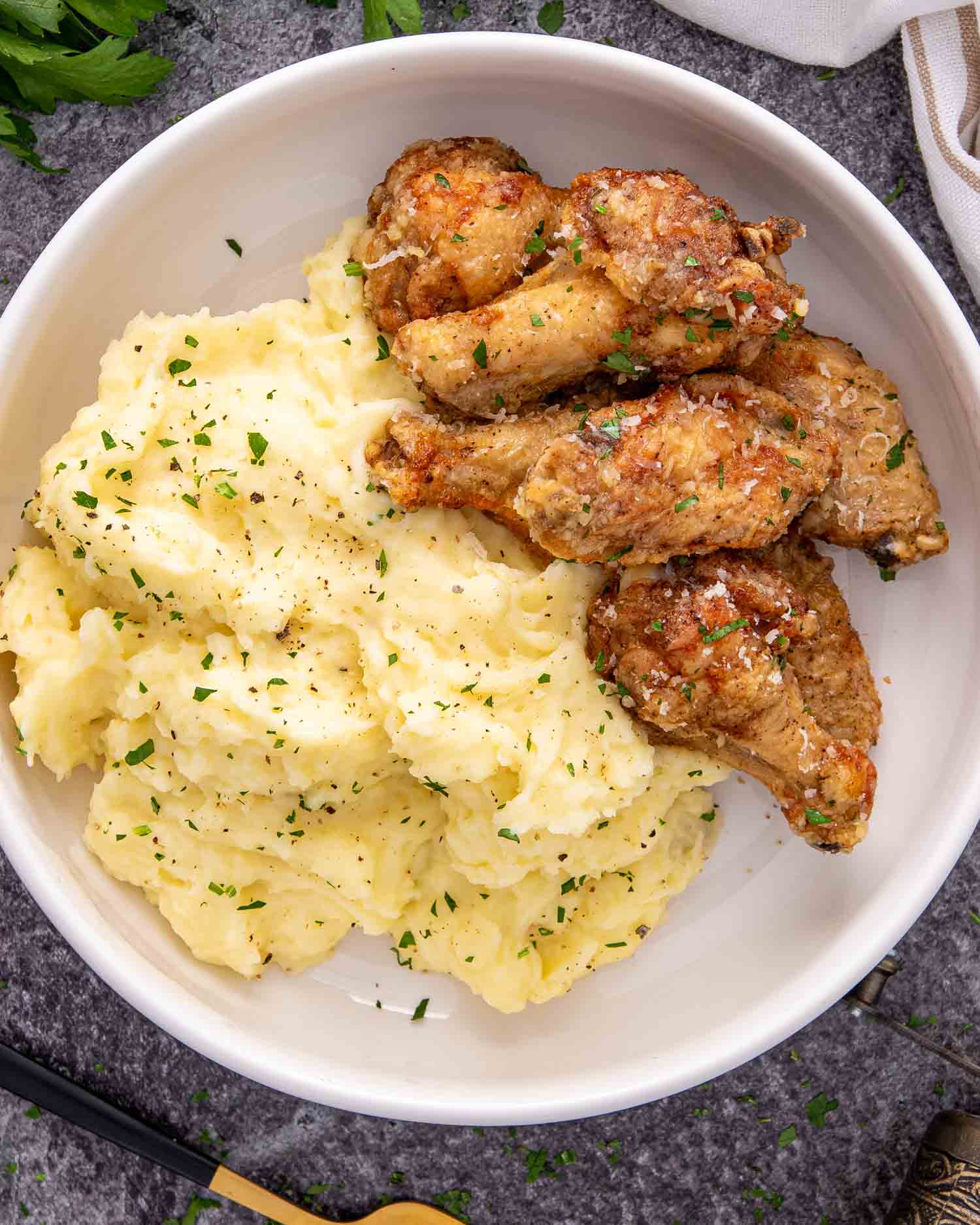 a white bowl loaded with mashed potatoes and crispy chicken wings.