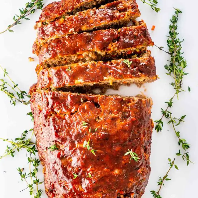 overhead shot of a meatloaf sliced on a white cutting board.