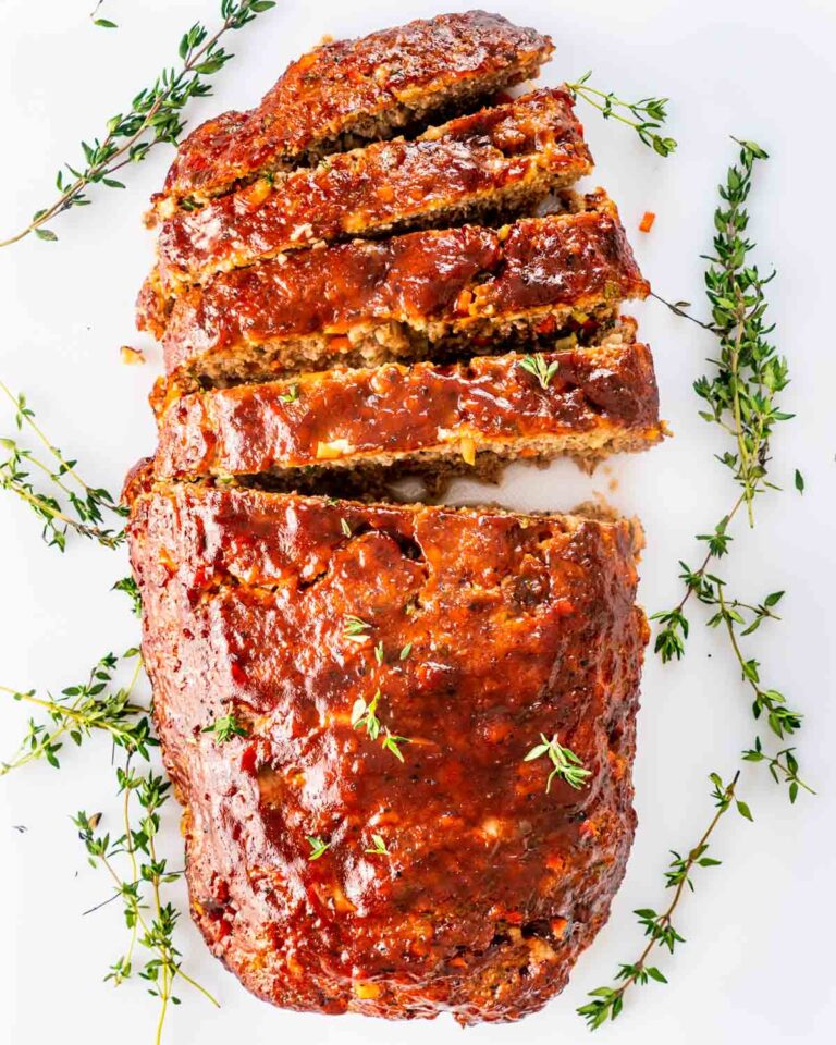 overhead shot of a meatloaf sliced on a white cutting board. 