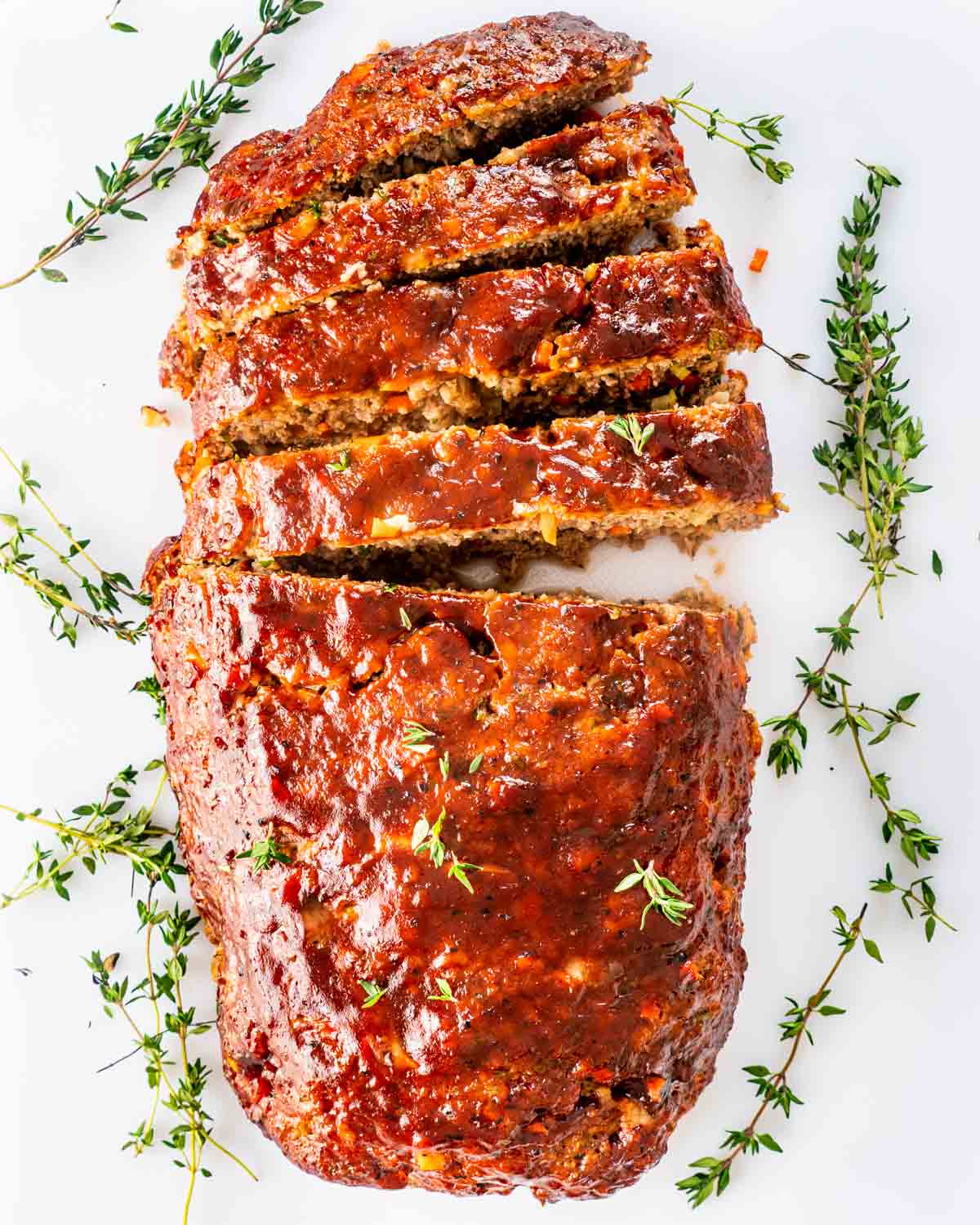 overhead shot of a meatloaf sliced on a white cutting board.