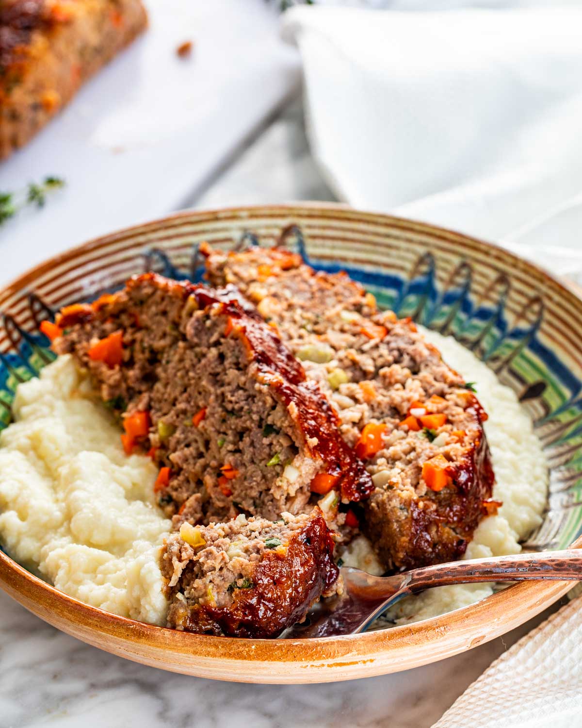 two slices of meatloaf over a bed of mashed cauliflower.