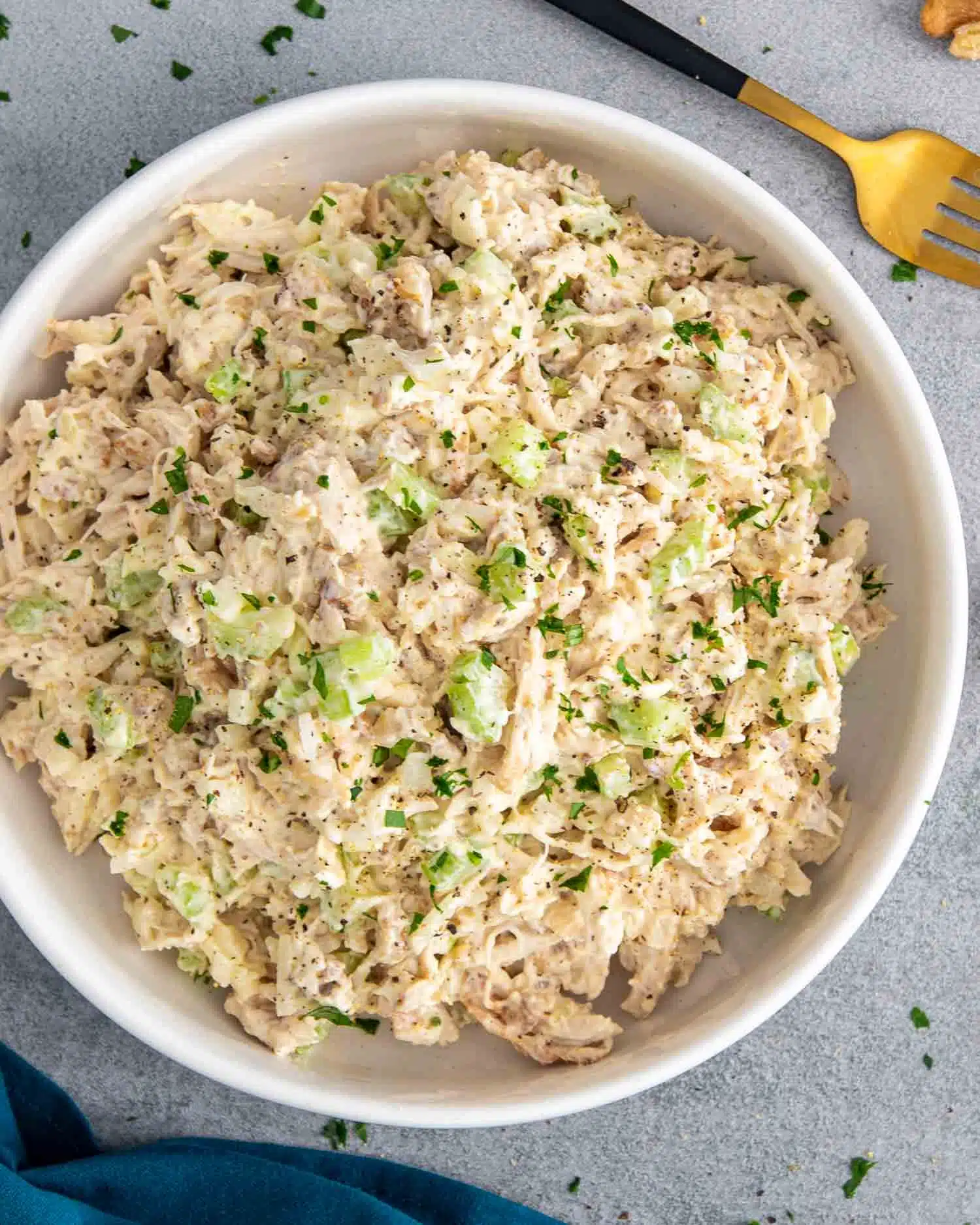 freshly made chicken salad in a white bowl garnished with a few extra crunchy walnuts.