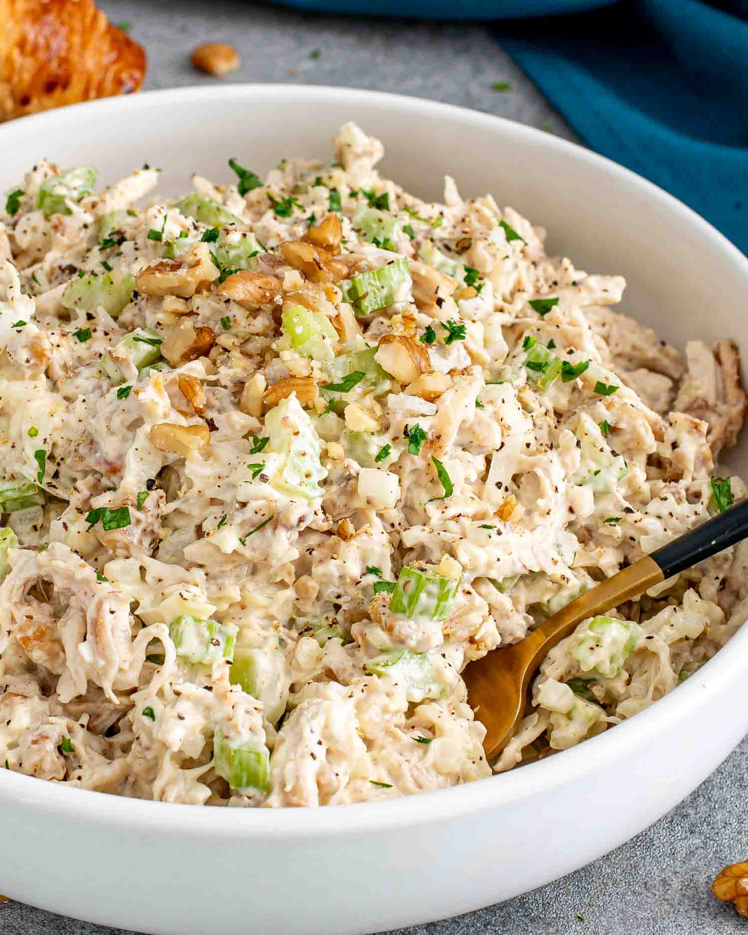 freshly made chicken salad in a white bowl garnished with a few extra crunchy walnuts.