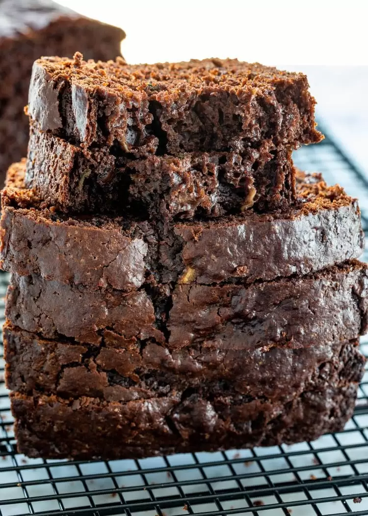 a stack of chocolate zucchini bread slices on a cooling rack