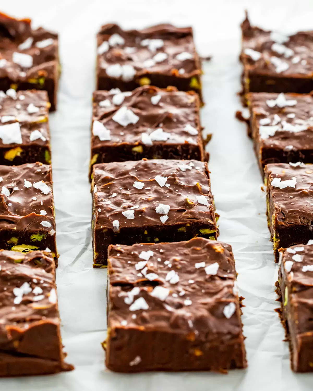 Easy Chocolate Fudge squares on parchment paper topped with flaked salt