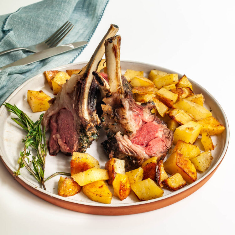 a plate with 2 lamb chops and roasted potatoes