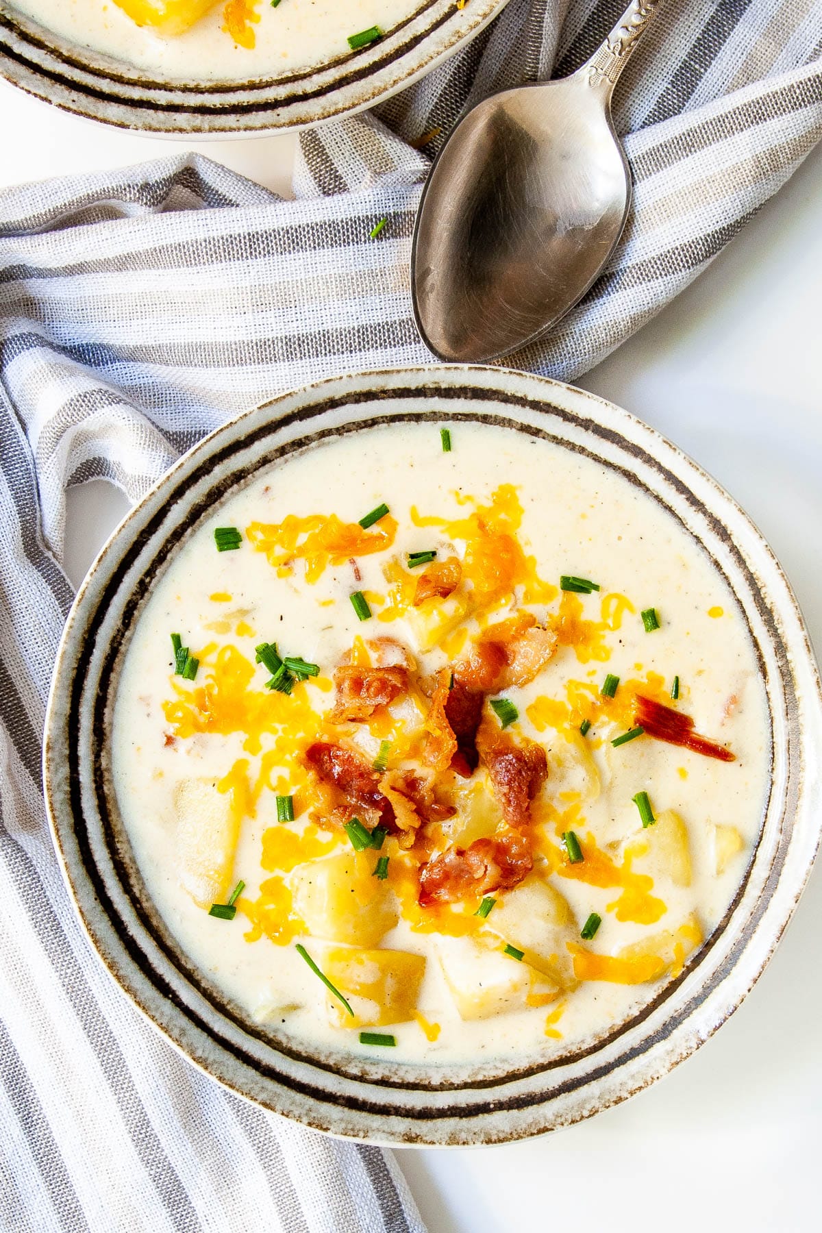 Baked Potato Soup in a bowl topped with cheddar cheese, bacon and chives