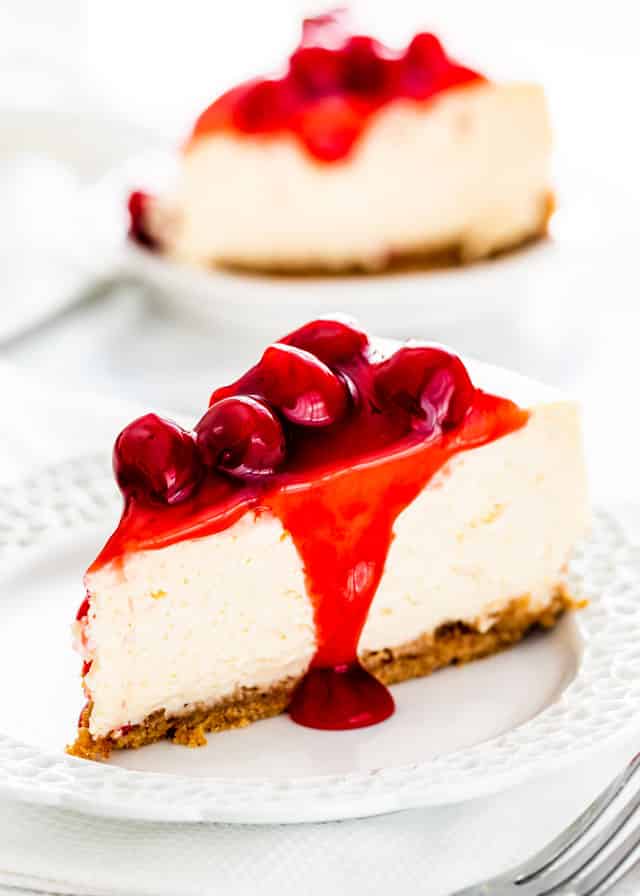 cheesecake slice topped with cherries on a white plate
