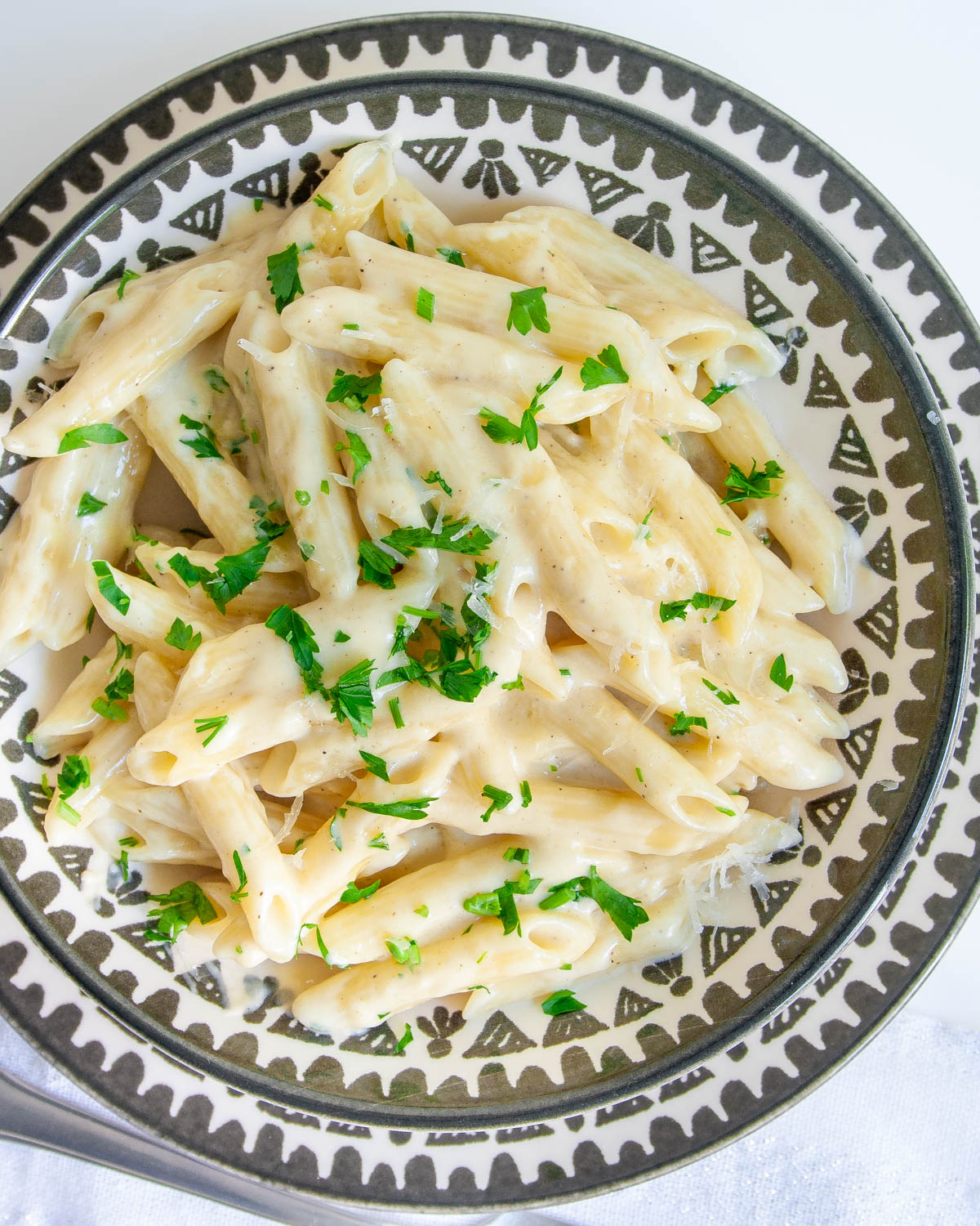 creamy parmesan pasta in a plate garnished with parsley