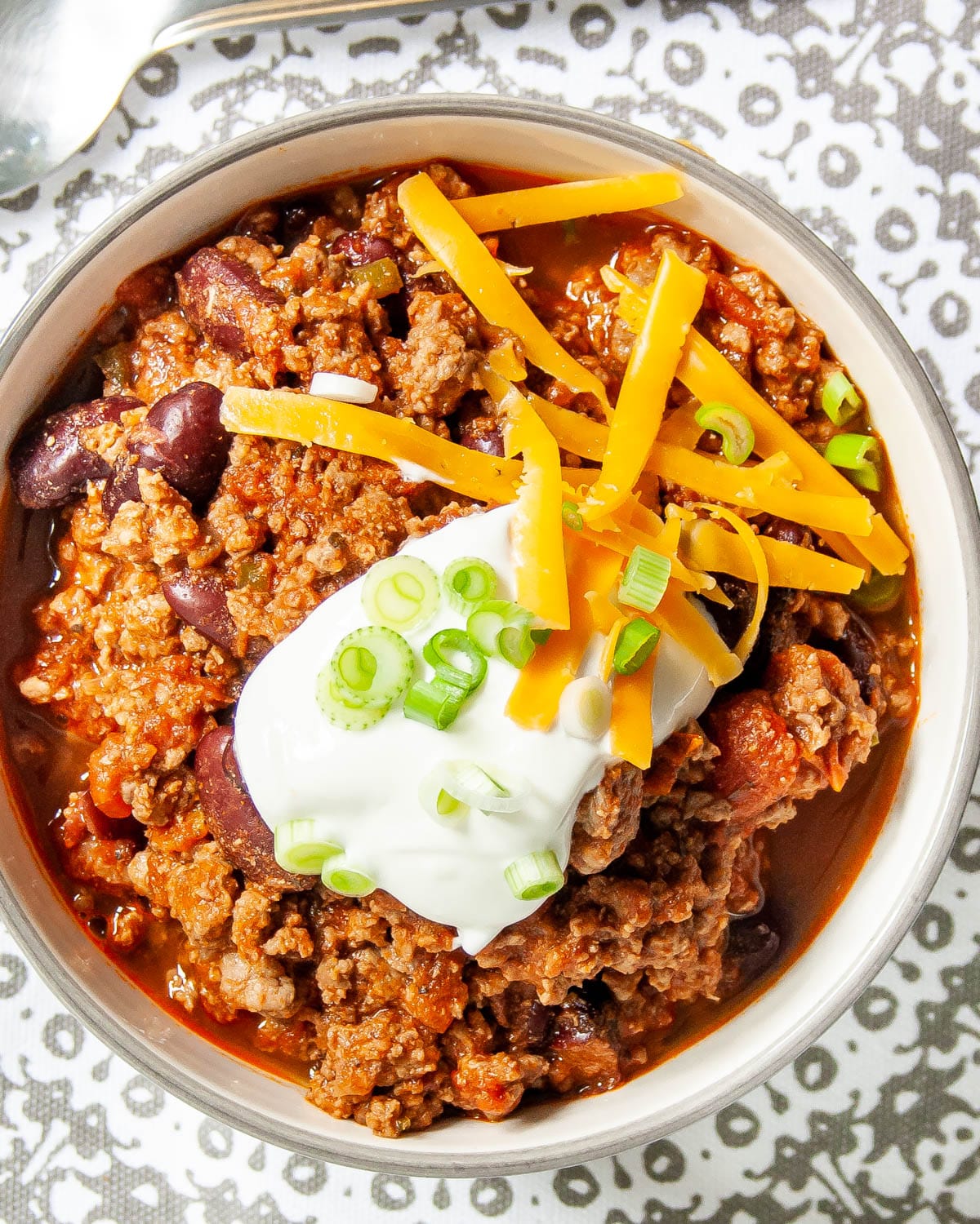 overhead shot of a bowl loaded with chili and topped with sour cream and cheddar cheese
