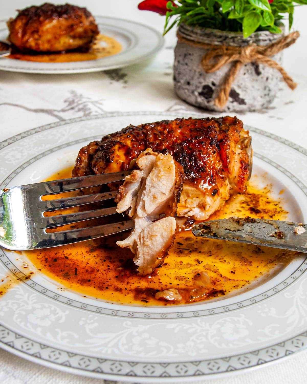 baked chicken thigh on a plate with a piece cut out of it
