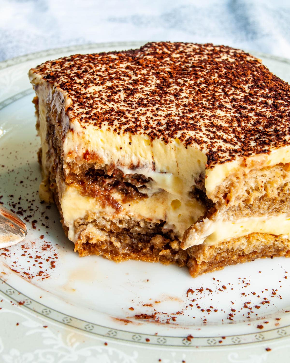 slice of tiramisu on a plate with bite taken out of it