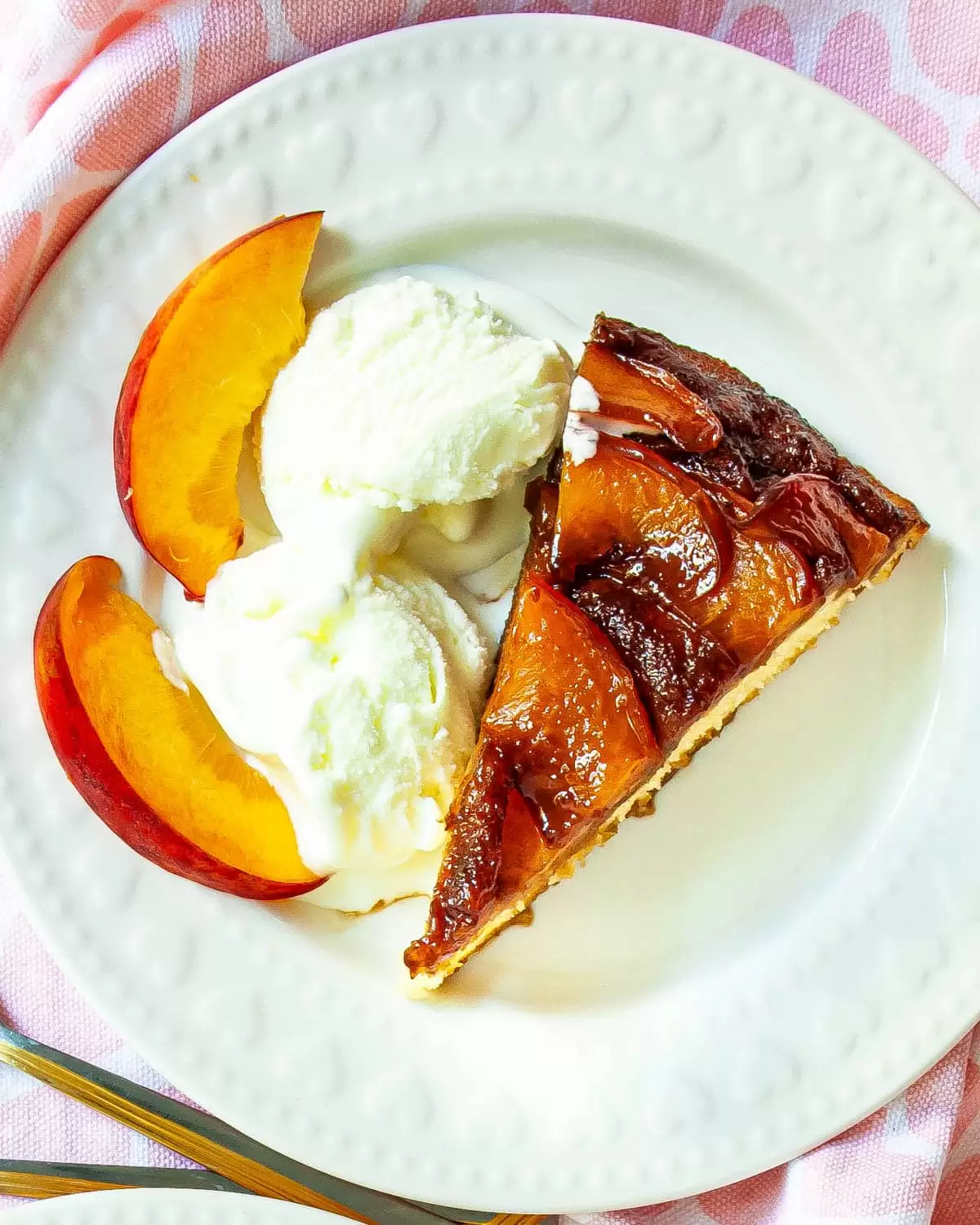 a slice of Peach Upside Down Cake with 2 scoops of ice cream on a white plate