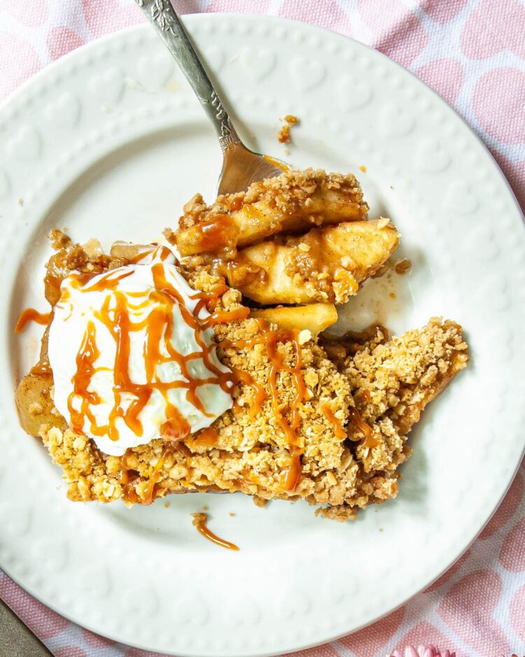 overhead shot of a slice of apple crisp on a white plate with a scoop of ice cream