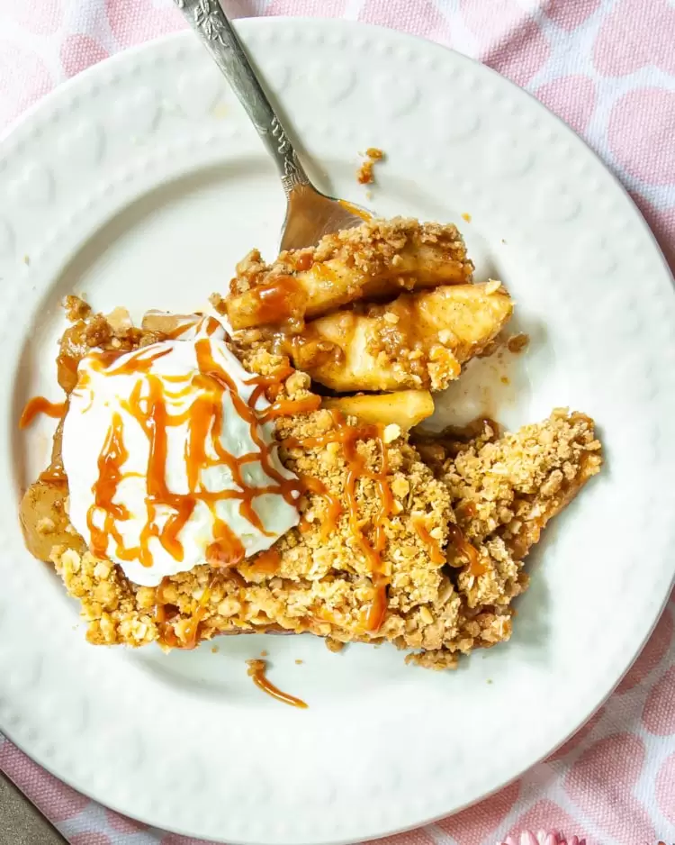 overhead shot of a slice of apple crisp on a white plate with a scoop of ice cream