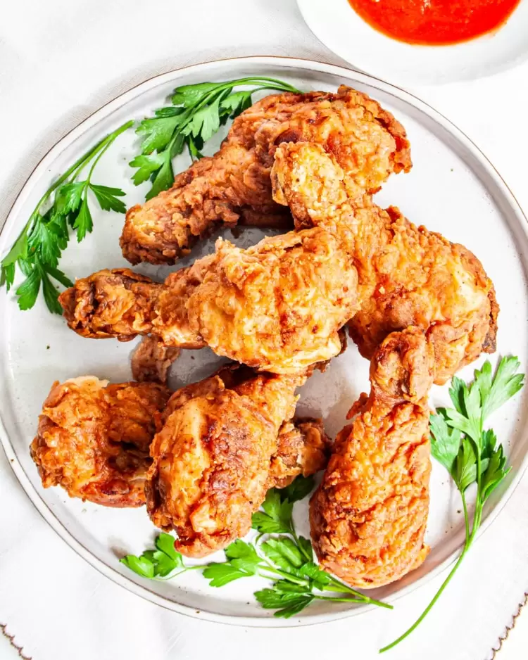 overhead shot of crispy fried chicken on a white plate garnished with parsley leaves
