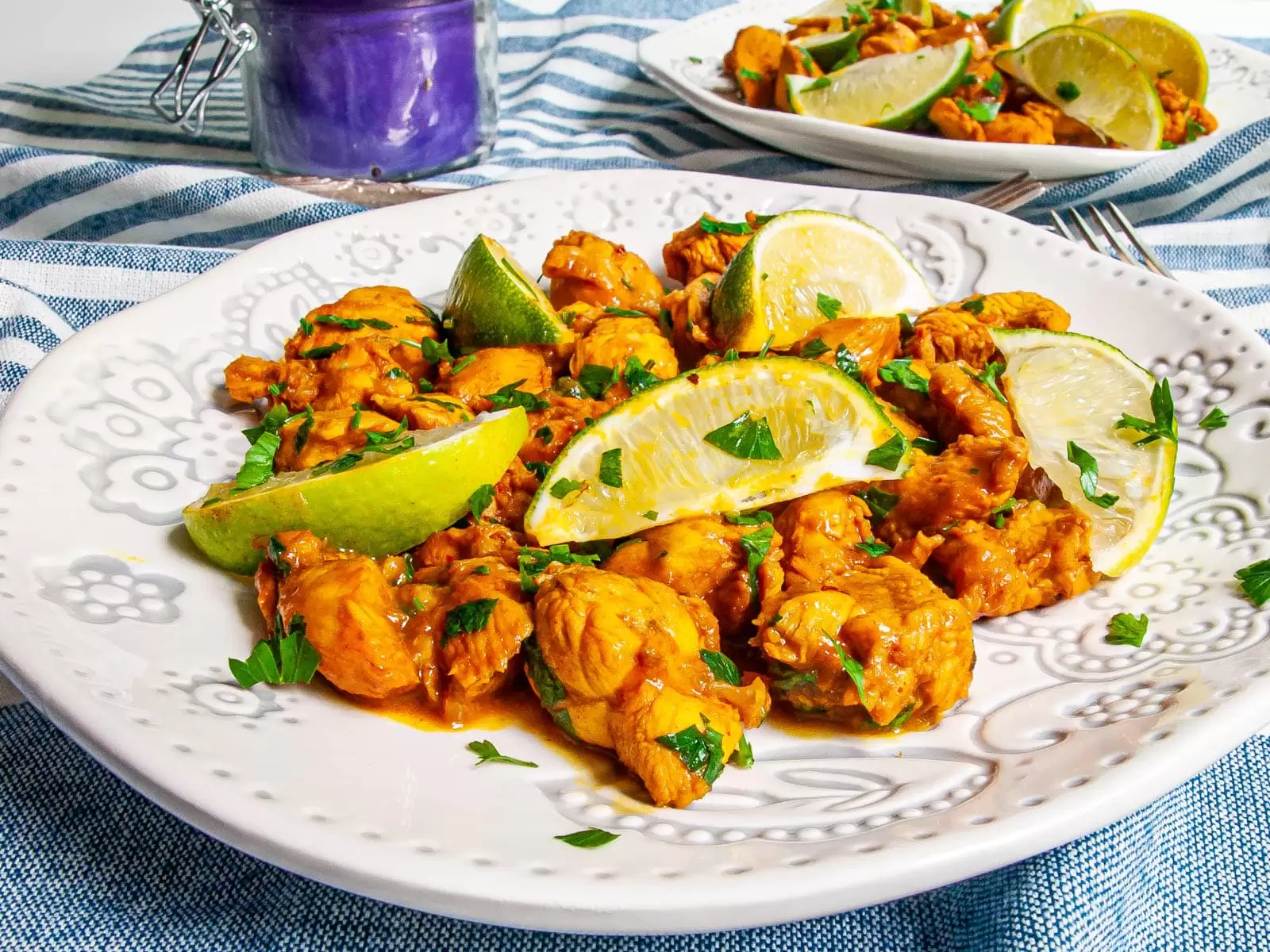 chicken satay in a white plate garnished with lime wedges