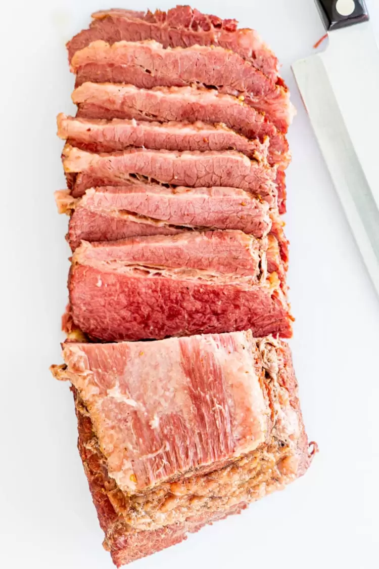 overhead shot of corned beef sliced up on a white cutting board