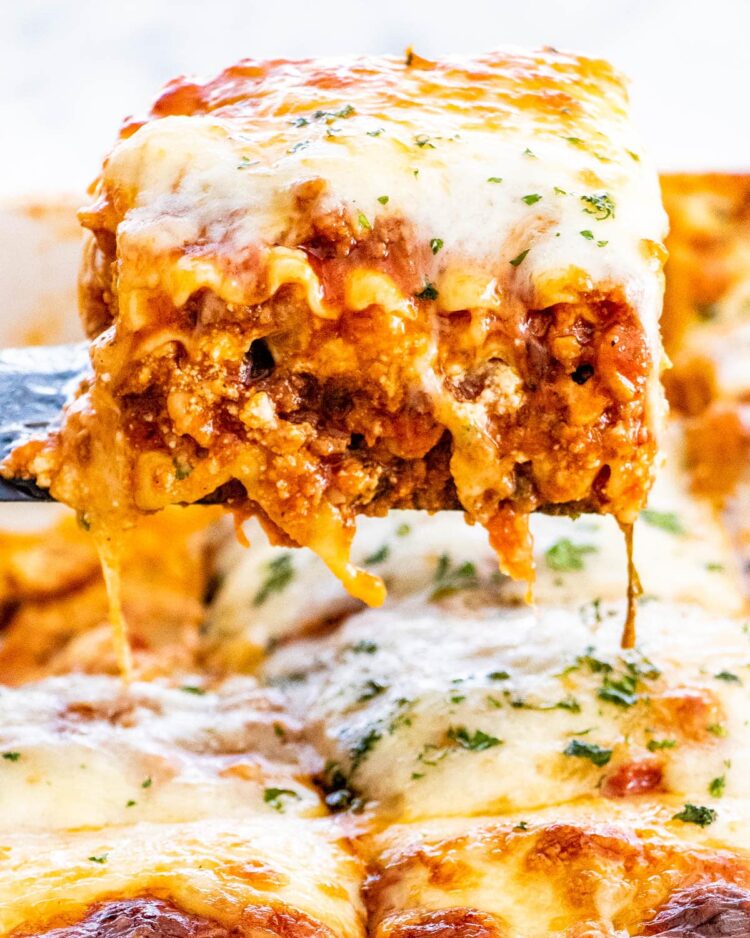 a spatula holding a piece of lasagna being picked up from a pan