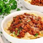 a serving of beef ragu over pappardelle in a bowl garnished with parsley.