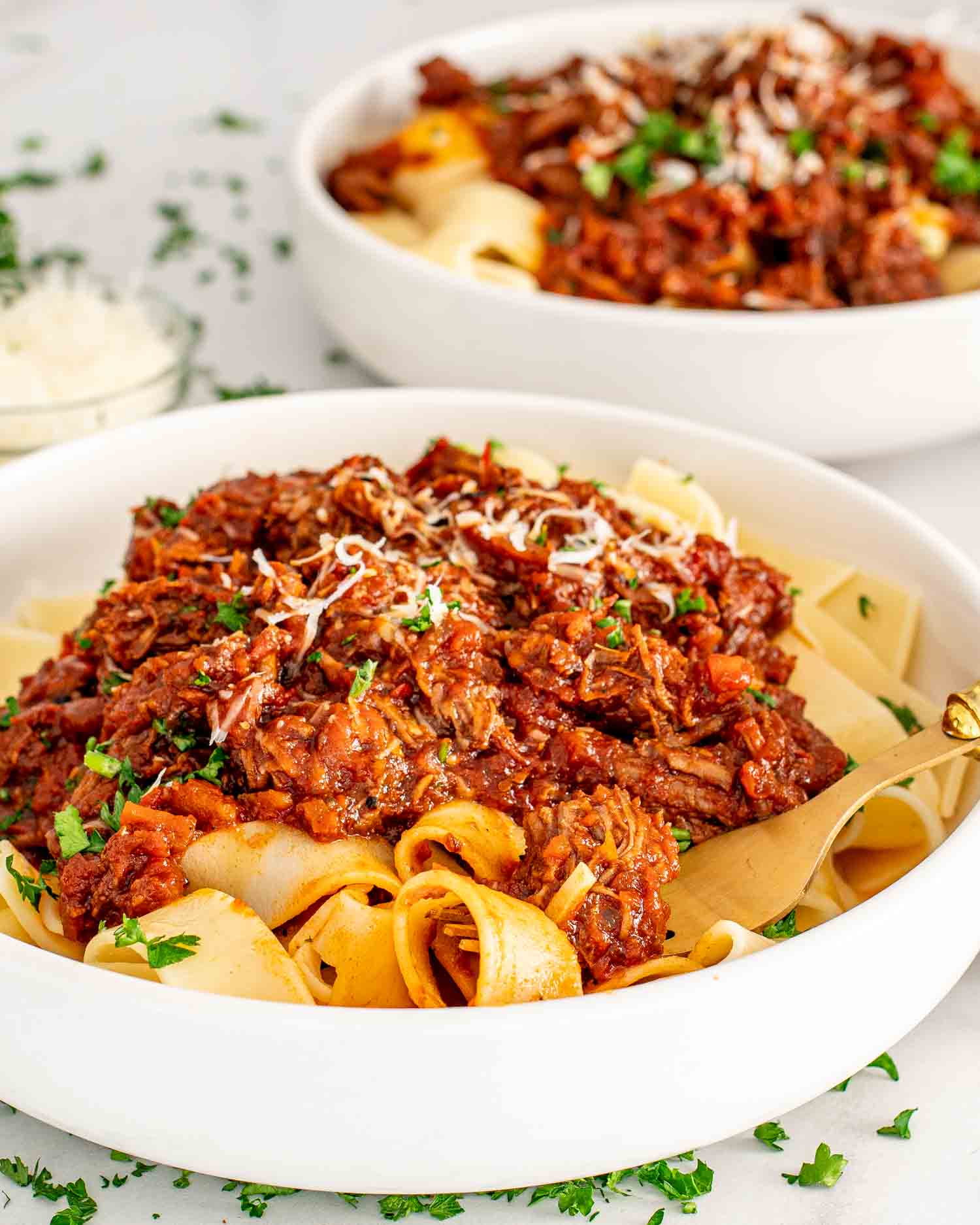 a serving of beef ragu over pappardelle in a bowl garnished with parsley.