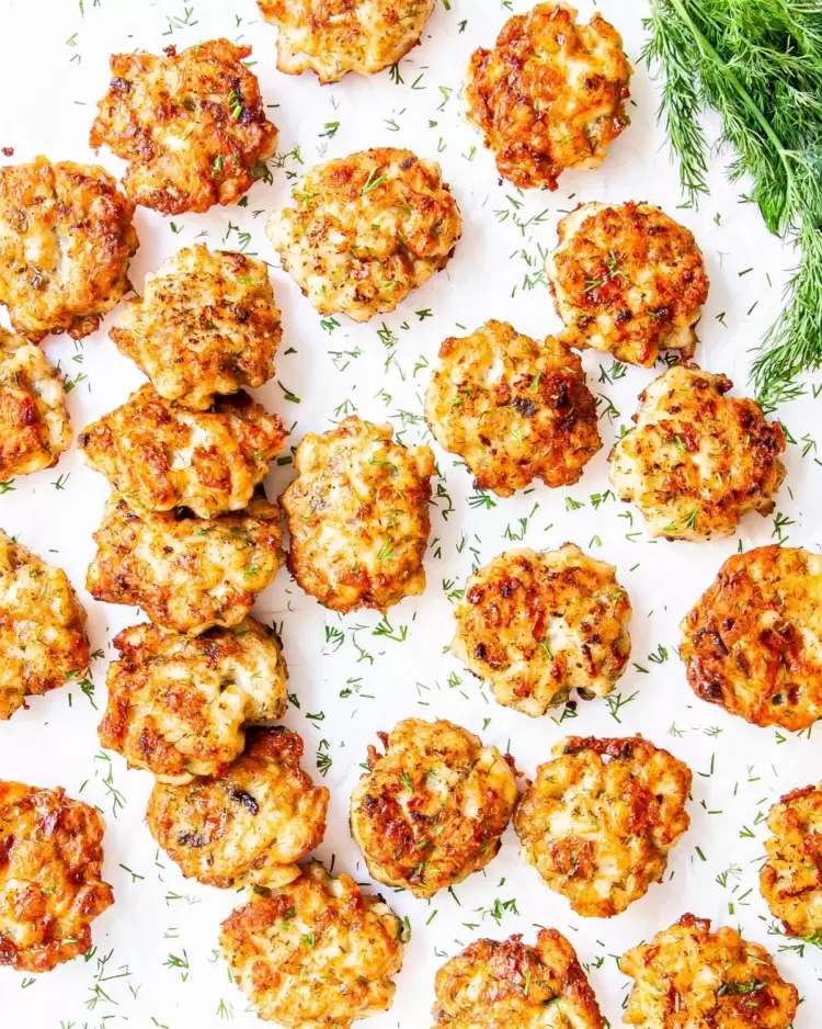 overhead shot of cheesy chicken fritters garnished with fresh dill