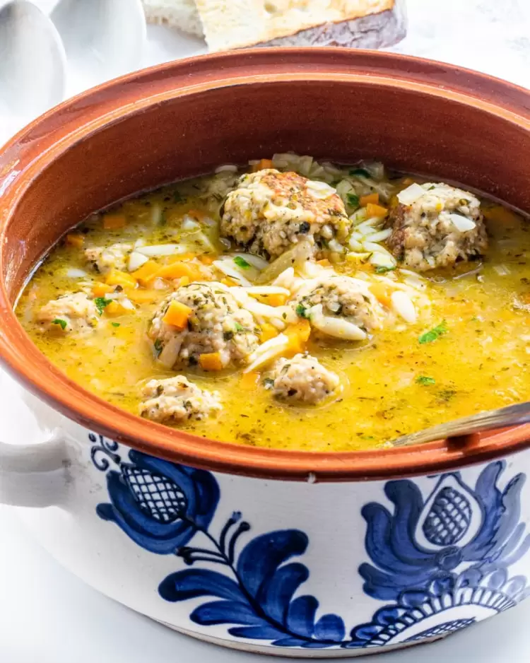 a big bowl filled with chicken meatballs and orzo soup