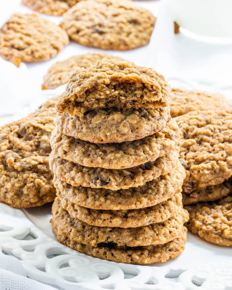 a stack of soft oatmeal cookies on a white plate with one cookie broken in half