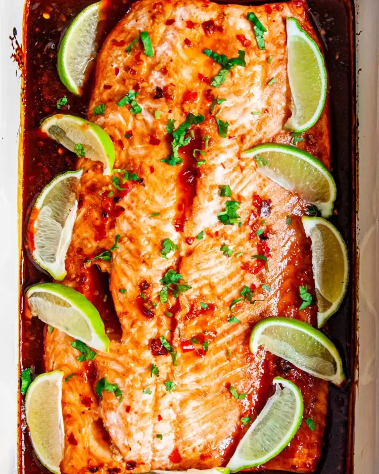 overhead shot of thai salmon baked in a  casserole dish garnished with lime wedges