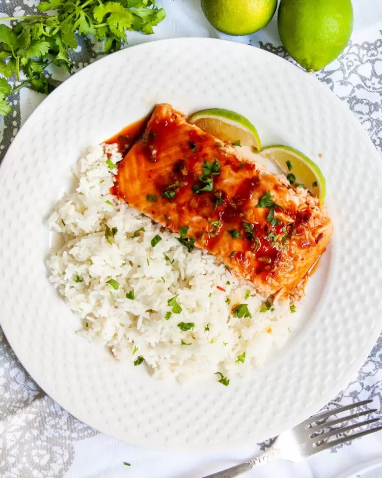 overhead shot of a slice of thai salmon with rice on a white plate