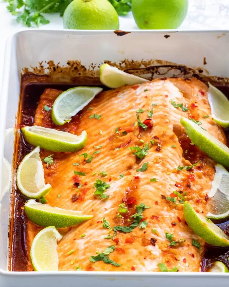thai salmon in a casserole dish with lime wedges