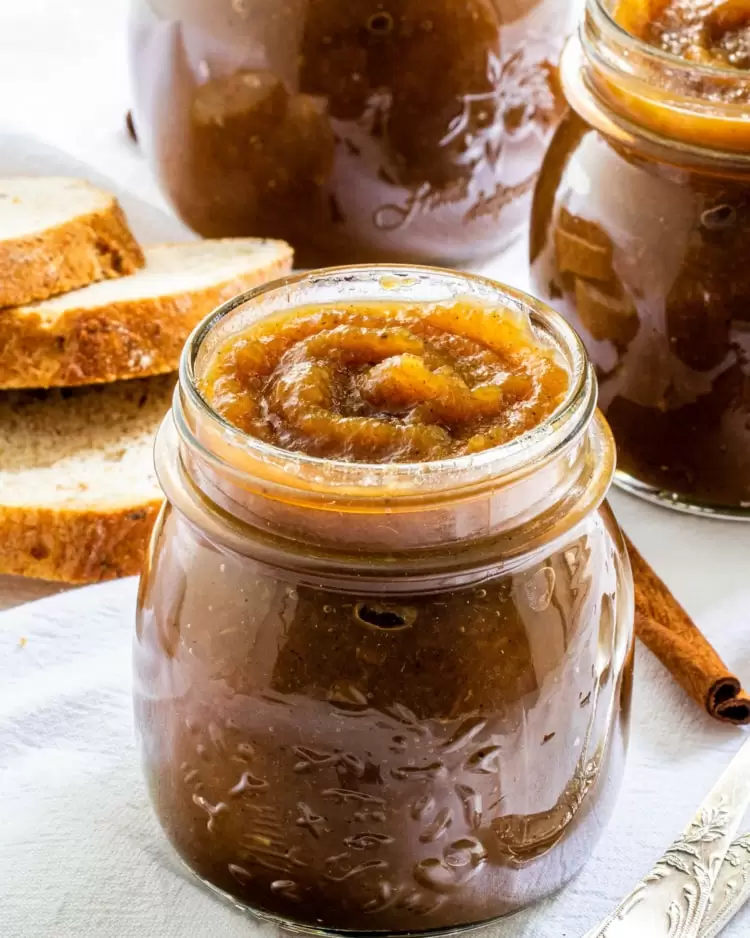 3 jars filled with apple butter and a couple slices of bread