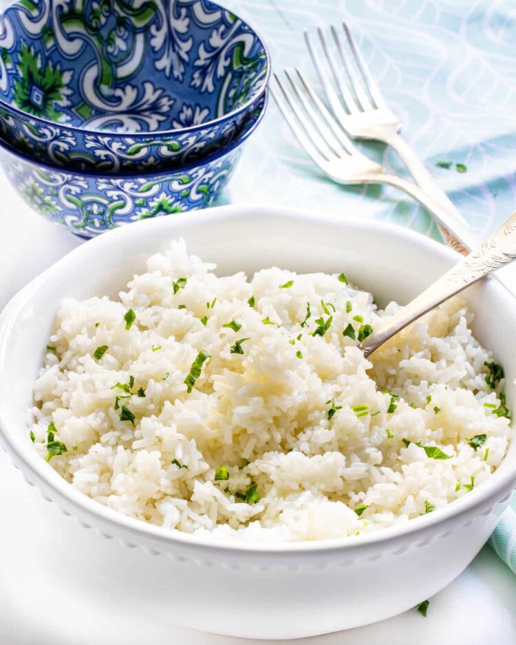 a white bowl loaded with rice and garnished with parsley