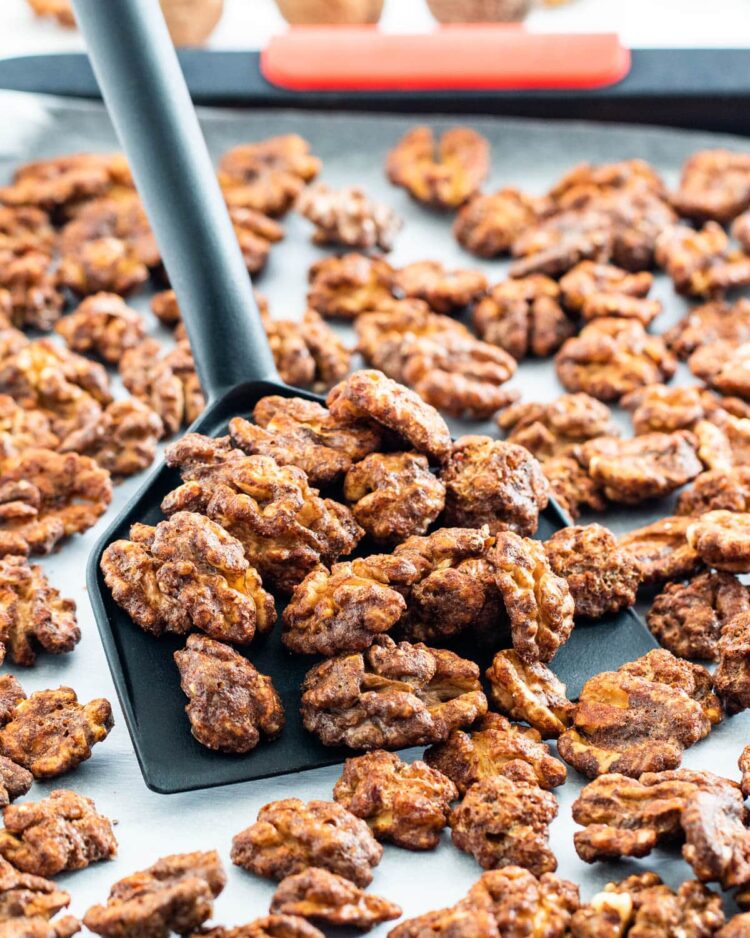 candied walnuts on baking sheet with a spatula holding some