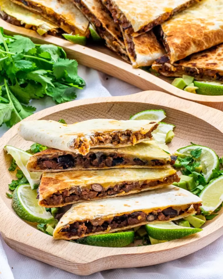 beef quesadillas cut into wedges on a wooden plate