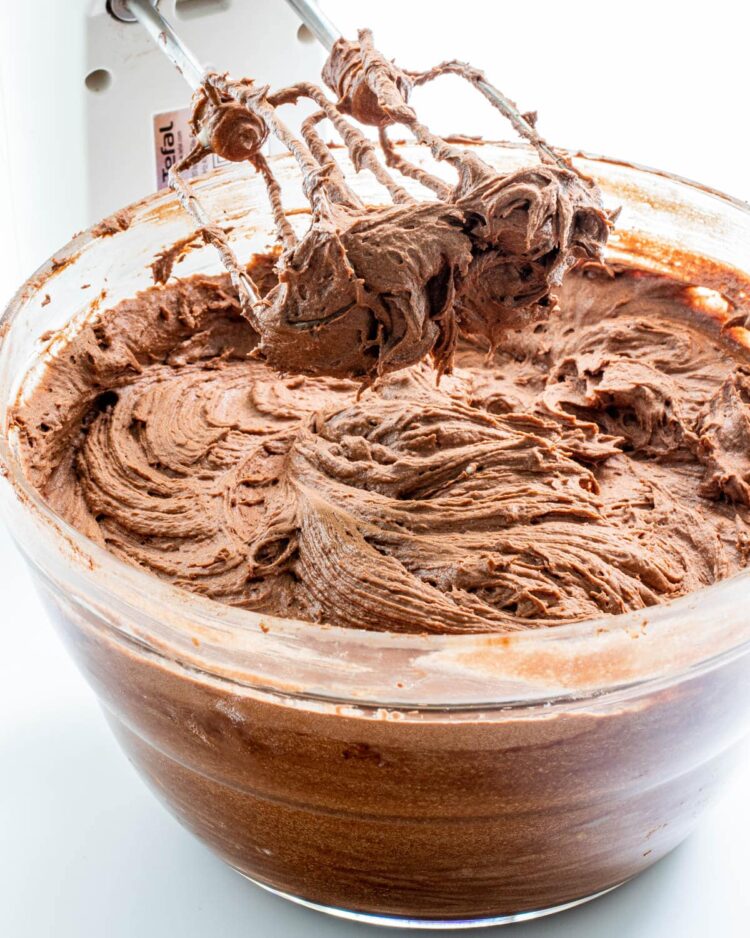 a bowl full of chocolate cream cheese frosting with beaters coming out of it