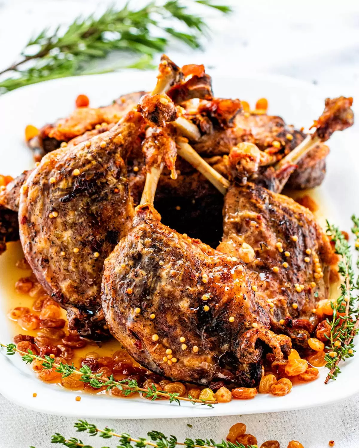 duck confit legs with pickled raisins on a white serving platter