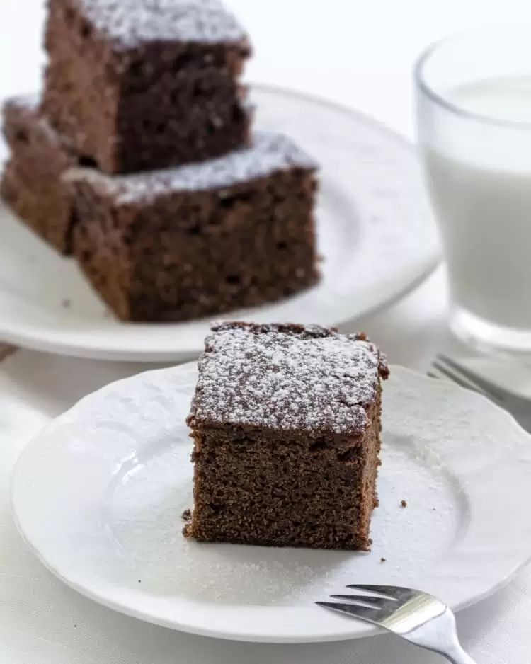 a slice of gingerbread cake on a plate sprinkled with powdered sugar