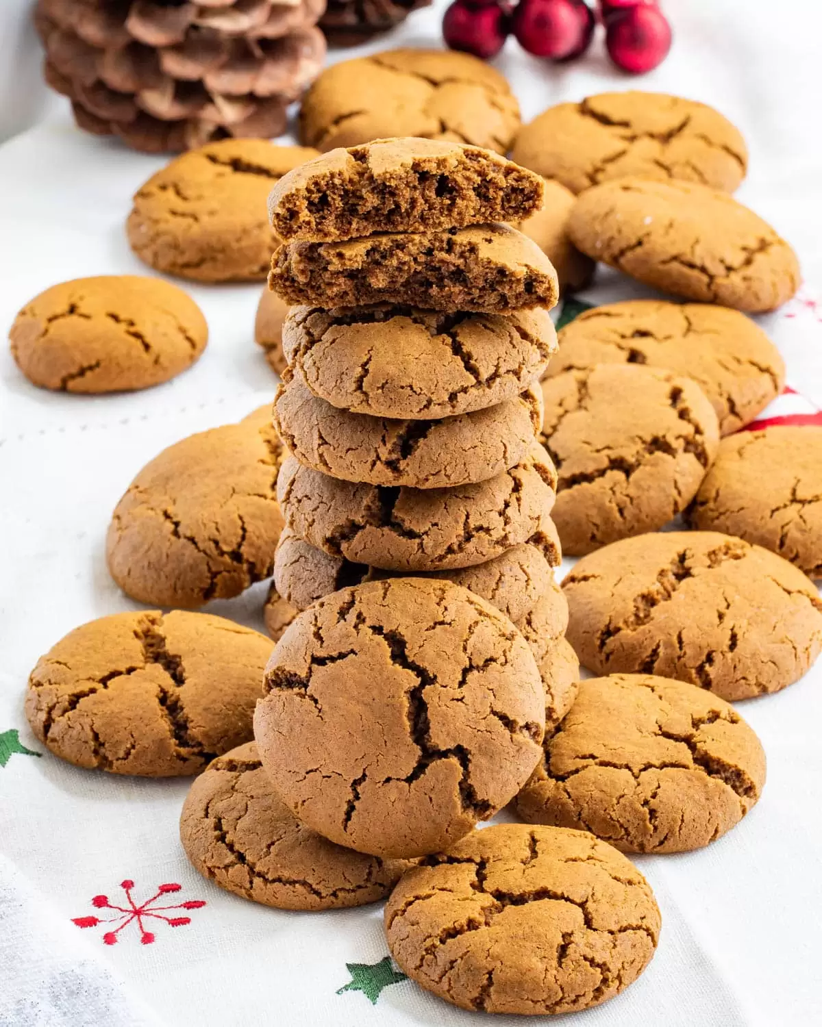 stack of chewy gingerbread cookies on a Christmas-themed table cloth.