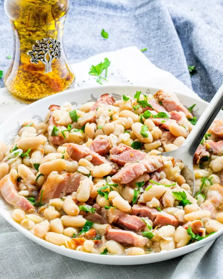 a plate loaded with tuscan white beans with a spoon in it