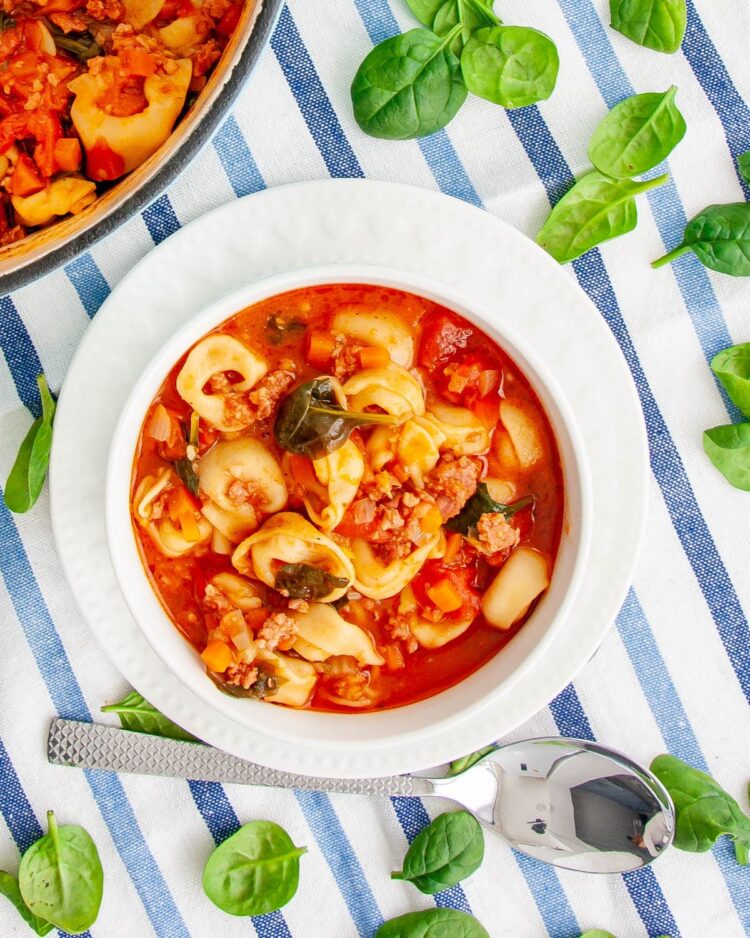 overhead shot sausage tortellini soup in a white bowl