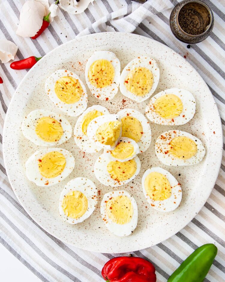 overhead shot of hard boiled eggs on a white plate sprinkled with spices
