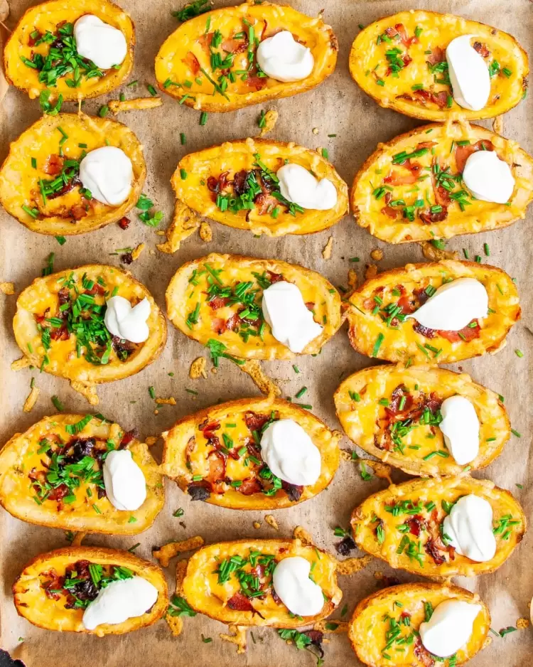 overhead shot of potato skins on a baking sheet garnished with sour cream and chives