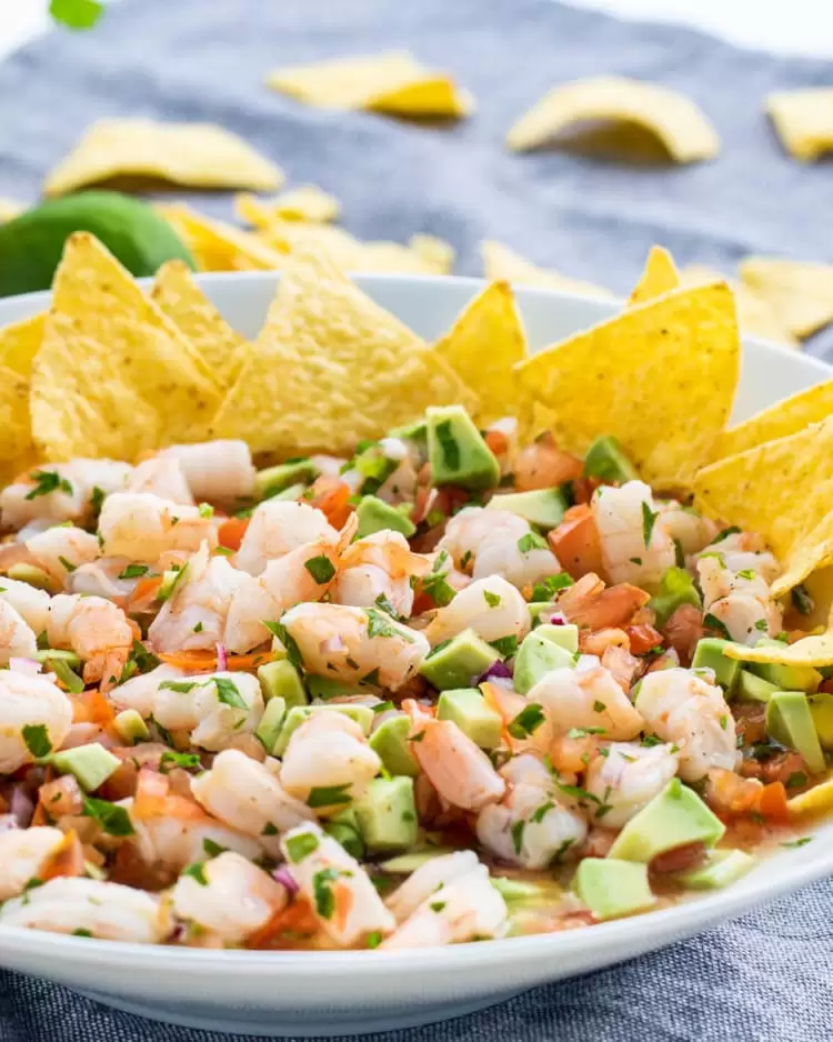 shrimp ceviche in a white bowl with tortilla chips on the side