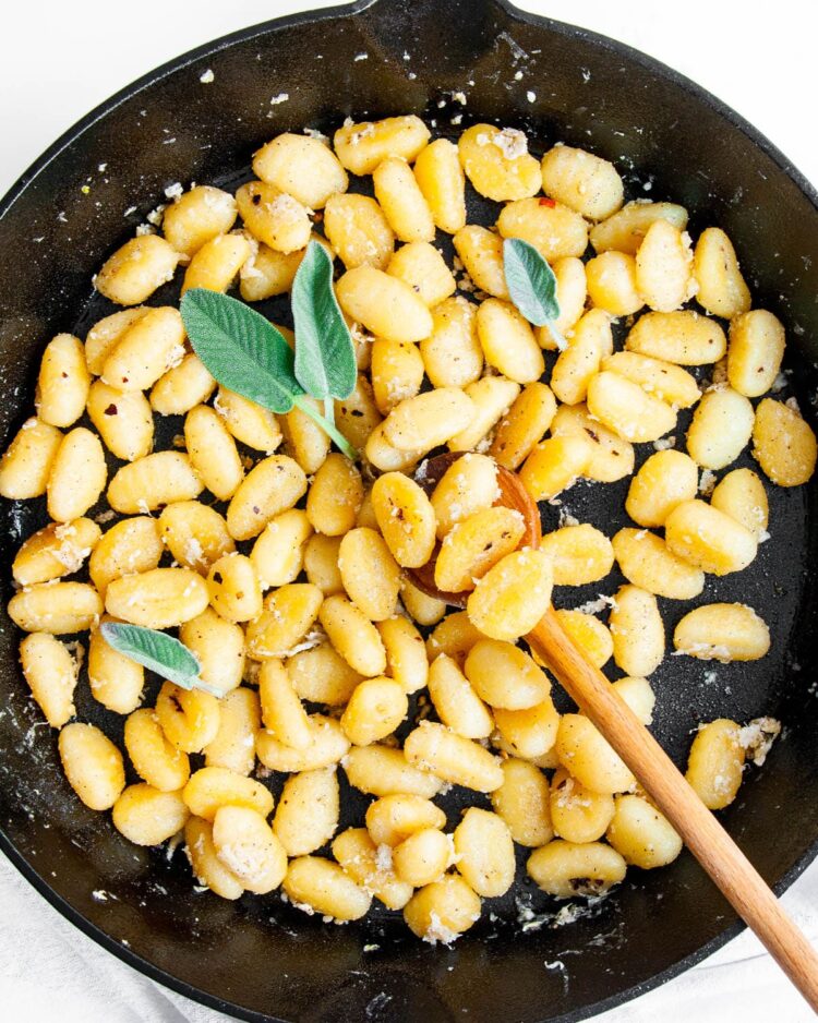 overhead gnocchi in a skillet garnished with sage and parmesan cheese