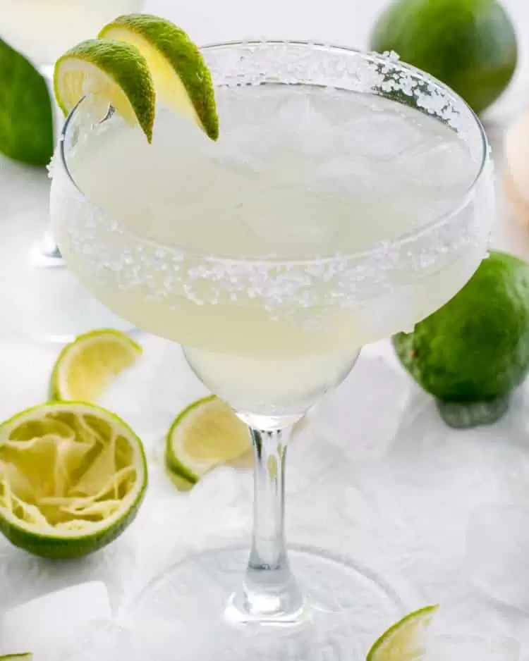 margarita in a rimmed glass with ice and lime wedges